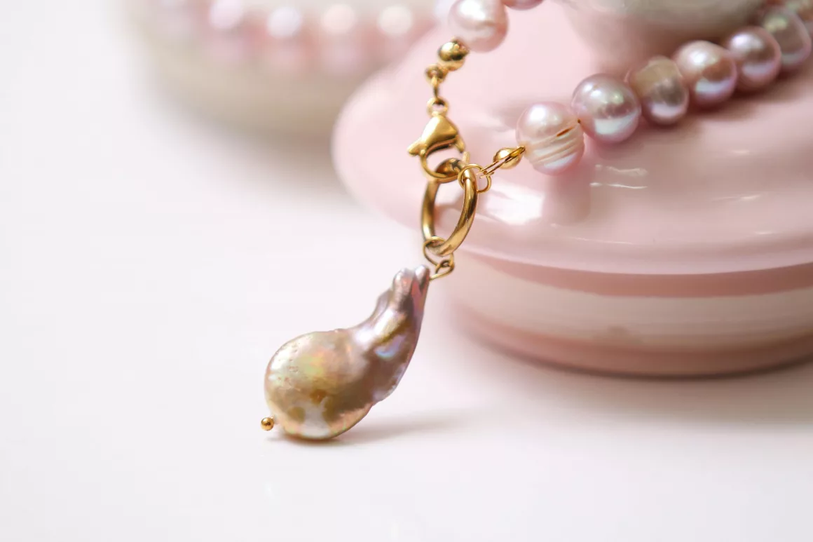 A close-up of a necklace featuring lustrous baroque pearls and a unique gold clasp, highlighting 2025 jewellery trends.