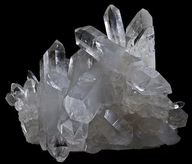 A cluster of clear quartz crystals, one of April’s Birthstones, showcasing their natural clarity and brilliance against a black background.