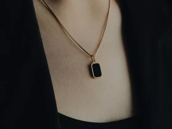 Close-up of a woman wearing a gold necklace with a rectangular black gemstone pendant, showcasing elegant black gemstone jewellery.