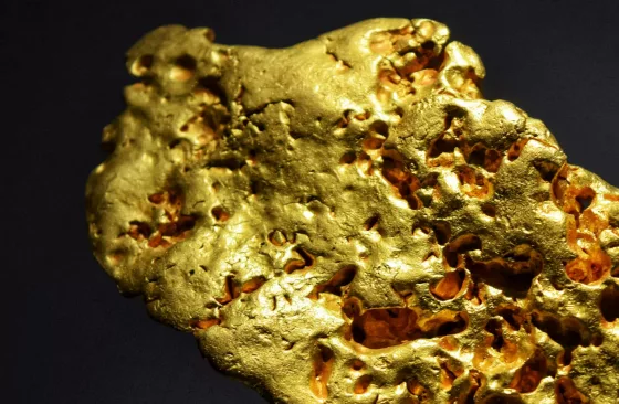 Large natural gold nugget on a dark background, representing physical gold investment for a gold ira.