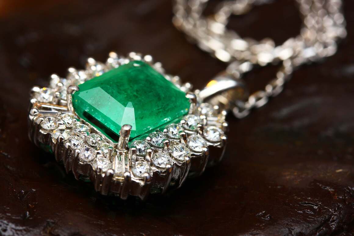 Close-up of an emerald and diamond pendant necklace, representing the May birthstone.