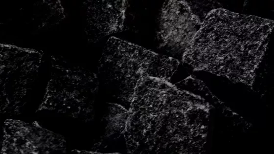 Mohs Hardness Scale - A close-up view of dark, rough-textured stone cubes with minimal lighting, creating a dramatic and moody atmosphere.