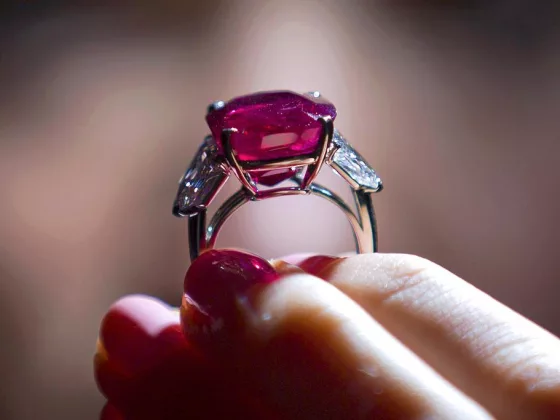 A close-up of a hand holding a ring set with the Sunrise Ruby, one of the world’s most valuable precious gemstones.
