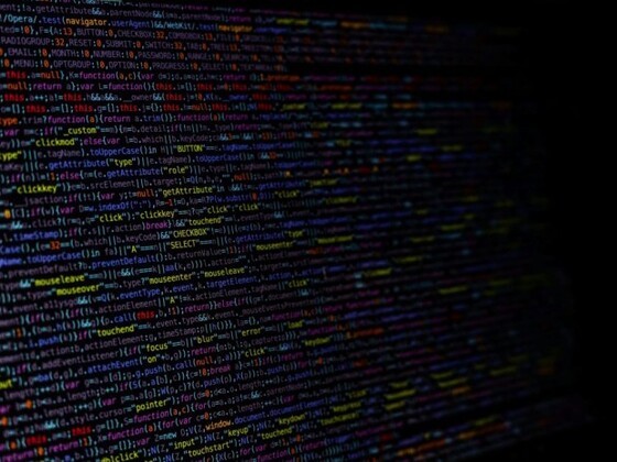 A dark computer screen filled with colorful lines of code, representing the advanced algorithms and digital processes behind AI gemstone certification.