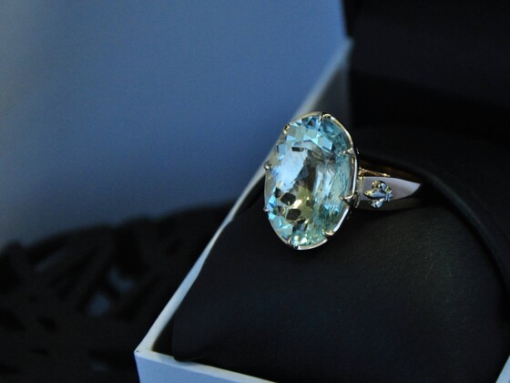 A close-up of a stunning aquamarine ring with a large, oval-cut pale blue gemstone set in a silver band, elegantly displayed in a black ring box, representing March birthstones aquamarine.