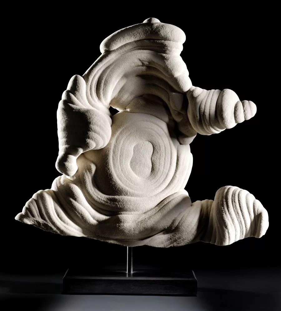 A large gogotte formation with intricate, swirling, and bulbous sandstone contours, displaying layered textures and cloud-like shapes, shown against a neutral background.