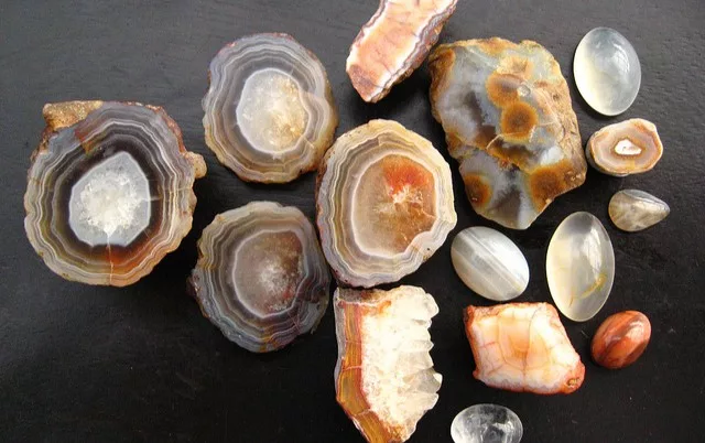 A collection of polished and raw Coal Hill agates from Tasmania, showcasing colorful banding and crystal interiors.