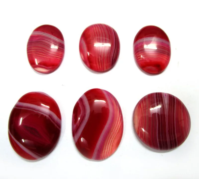 A collection of polished red and white banded oval cabochon stones known as sardonyx, displaying layered stripes and a glossy surface, exemplifying a distinctive gemstone associated with august birthstones.
