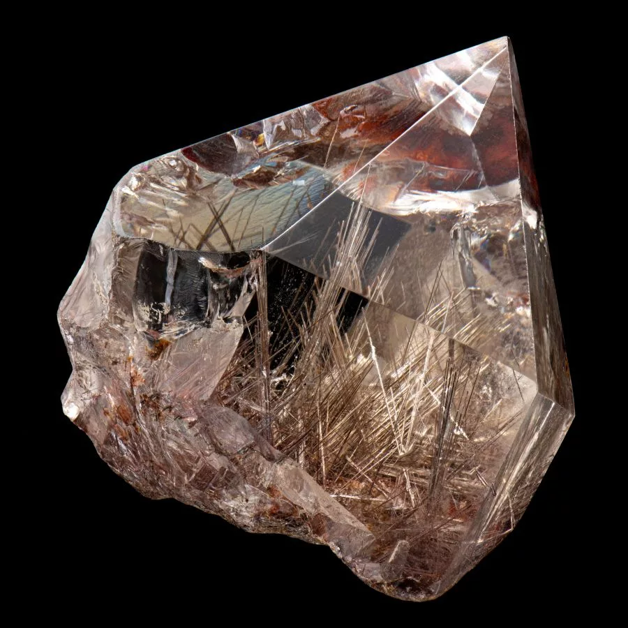 Rutilated Quartz crystal with golden needle-like rutile inclusions in a polished and faceted form on a black background.