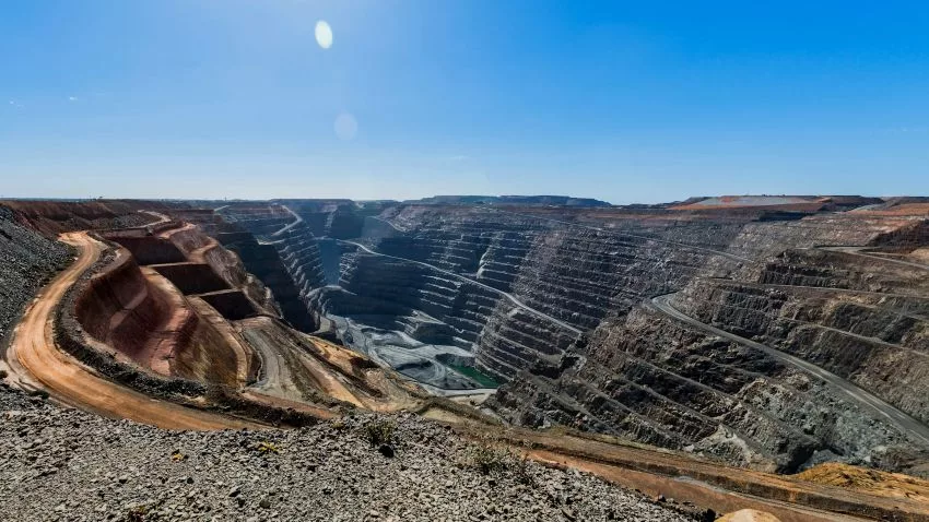 A panoramic view of the Super Pit gold mine in Western Australia, showcasing terraced rock walls, winding haul roads, and the immense scale of open-pit mining under a clear blue sky—an iconic site among Geological and Mineral Destinations in Australia.
