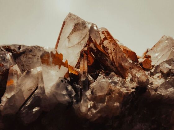 A close-up view of natural quartz crystals with translucent points and brownish mineral inclusions, highlighting the raw beauty and geological structure of quartz.