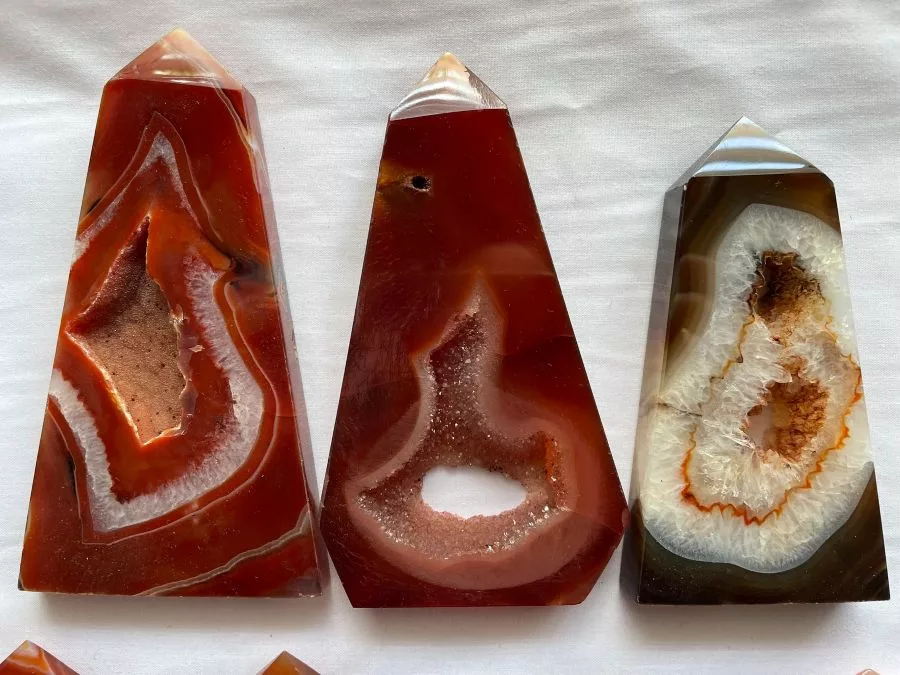 Three Carnelian slab towers with druzy crystal formations, displayed upright on a white cloth background.