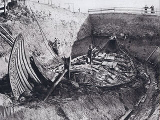 Black and white photograph of the Oseberg ship excavation in Norway, an elaborate Viking ship grave discovered in a burial mound, one of the most famous examples of Viking Burials.