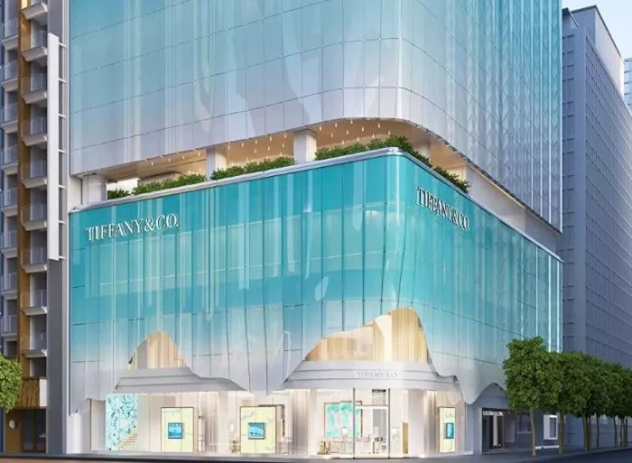 Tall, modern turquoise-blue glass building with "TIFFANY & CO." signage on two levels, identified as the Tiffany & Co Tokyo flagship store, representing Tiffany & Co. in 2025.